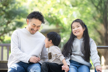 新緑の背景で公園で遊ぶ笑顔の仲良し親子