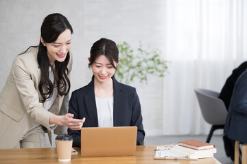 Business scene of a senior teaching a newcomer to work at a desk and a junior being taught.