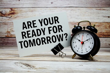 Are your ready for tomorrow? text on paper card with alarm clock on wooden background