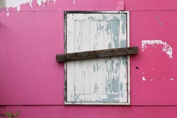 Old window closed permanently, pink wall of abandoned building