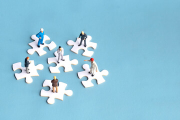 Miniature people standing on jigsaw puzzles. Concept of work collaboration