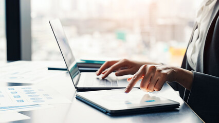 Female business person working on laptop and tablet PC in urban office building