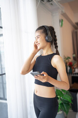 Fitness asian woman using smart phone and headphones Enjoy listening to music. Female with headphones smart phone after workout