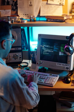 Unrecognizable Hacker Writing Code on Old Computer