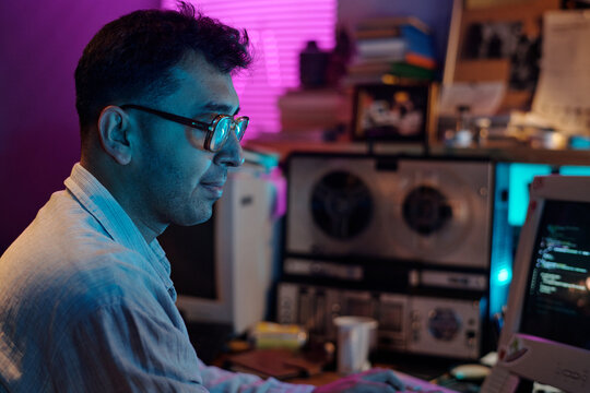 Young male Indian programmer writing code on retro computer , copy space