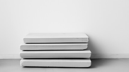 Stack of four white mattresses stacked on top of each other against a plain white wall. the mattresses appear to be made of a soft, plush material and are neatly arranged in a horizontal manner.
