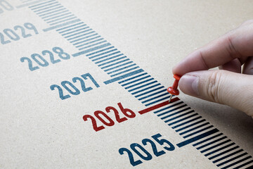 Red pin marks year 2026 on brown paper. Start the new year concept, transition from 2025 to 2026...