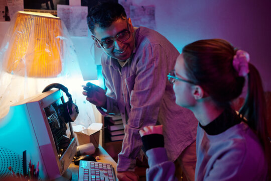 Two diverse young hackers discussing code errors while using retro computer in small room