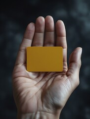 Close-up of a hand holding a yellow card against a dark moody background, symbolizing warning, authority, or decision-making in various contexts like sports, business, or security

