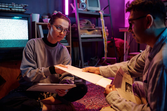 Young man and woman examining white folders labeled top secret while working together sitting on floor