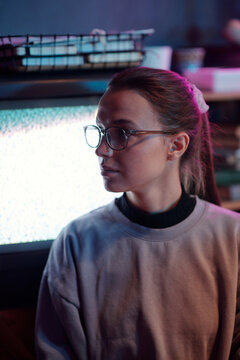 Chest-up portrait of confident Caucasian girl wearing glasses looking away, CRT television with no signal message in background