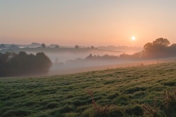 Obraz premium A tranquil countryside scene with soft fog lifting over rolling hills, revealing a vibrant sunrise in the distance, A peaceful countryside scene with fog slowly lifting as the sun begins to rise