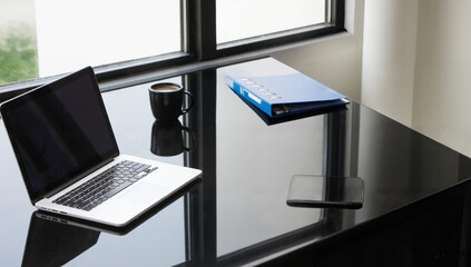 Modern workspace featuring a sleek laptop and notebook on a glossy desk, natural light streaming...