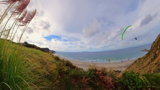 Paragliding soaring fast above a beautiful New Zealand beach. Extreme aerial adventure and freedom concept.