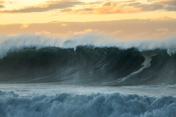 Large waves crash along Sydney’s rocky coastline at sunrise.