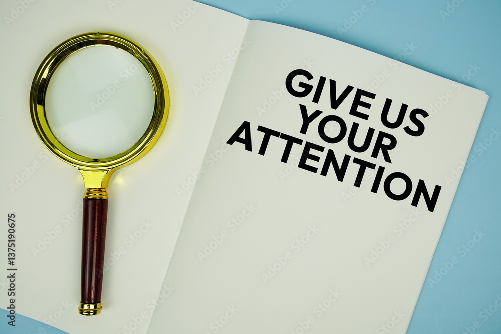 Poster give us your attention text with magnifying glass flat lay on notepad background