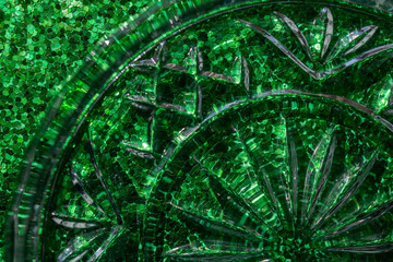 Full frame macro abstract texture background of a crystal glass coaster on sparkling green glitter surface with copy space