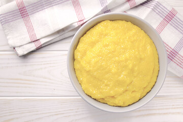 Delicious corn porridge in a bowl on a white wooden table.