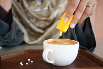 Adding sweetener to a cup of coffee in a cozy cafe setting
