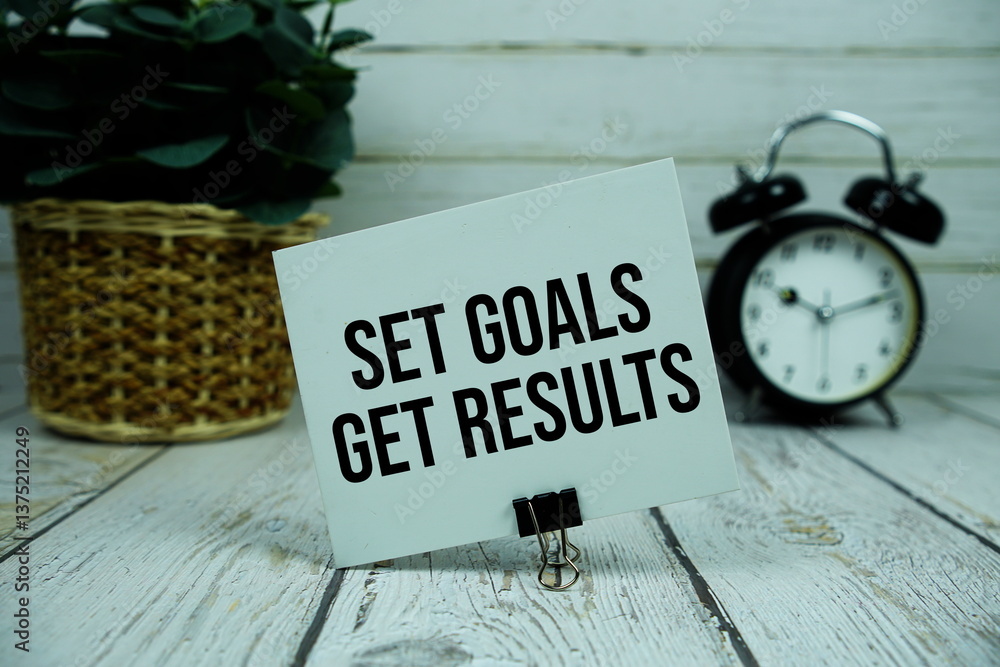 Poster set goals get results text on paper card with alarm clock on wooden background