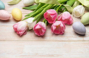 Easter eggs and pink tulips resting on white wooden table