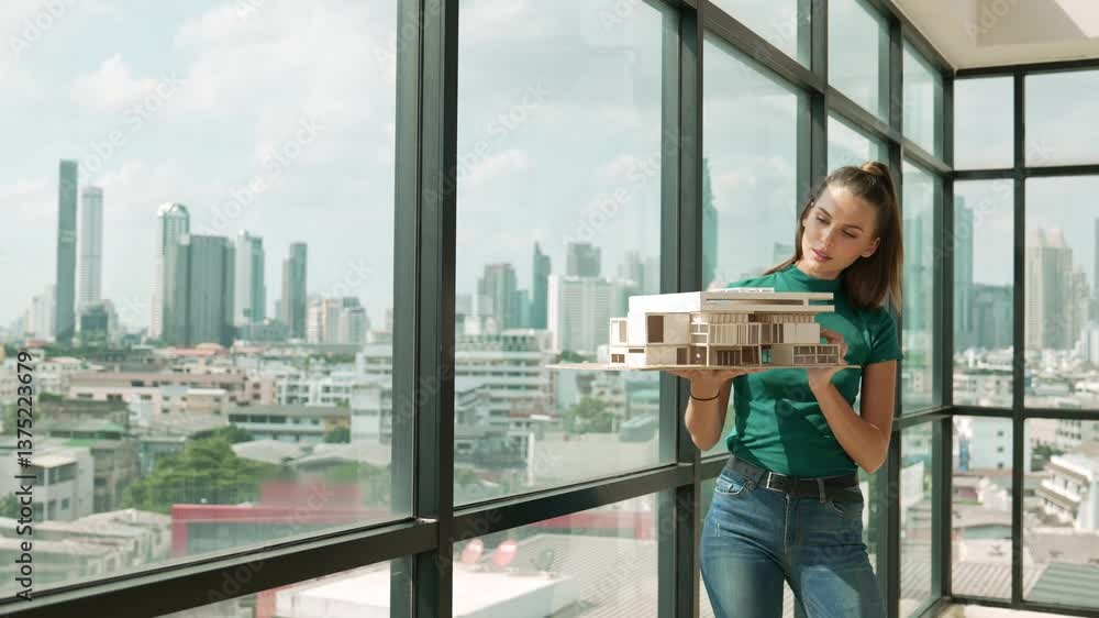 Poster young happy beautiful engineer check house model by turning left side and right side. professional m