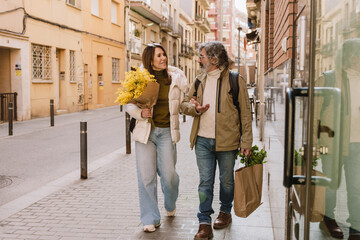 A middle-aged White couple of a husband and wife in their 50s, taking a stroll together on a city...
