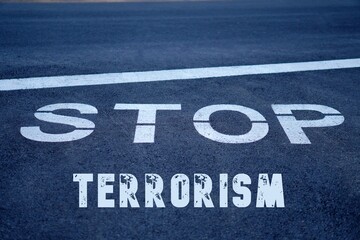 stop terrorism concept.words written next to a stop sign on the asphalt of the road.