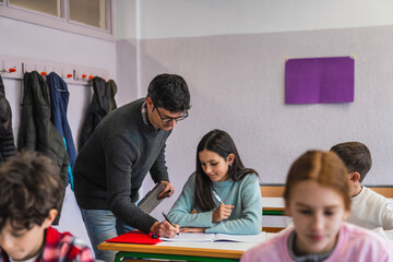 Teacher helping student with exercise in classroom