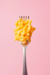 Close up view of delicious mac and cheese on a silver fork against pastel pink background