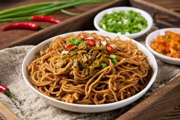 bowl with traditional hot and dry noodles on wooden table.