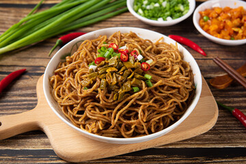 bowl with traditional hot and dry noodles on wooden table.