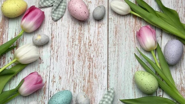 Easter eggs and tulips forming a border on rustic white wood