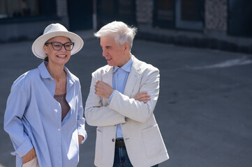 Stylish elderly laughing couple on a walk. Romantic relationships of mature people. 