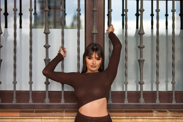 young woman with cosmetic operations on her lips and cheekbones grabs the grille of a window. The...