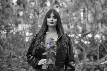 Portrait of Spanish woman, brunette with long hair and only black jacket posing with a flower...