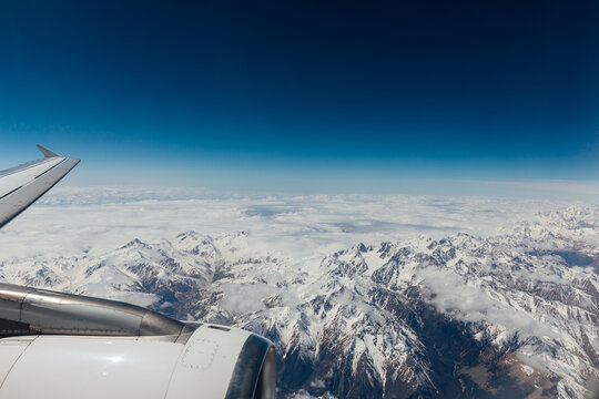 Beautiful landscape on snowy mountains with clouds from the window of an airplane