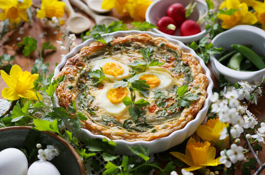 Easter quiche, tart with boiled eggs, vegetables and herbs in a casserole dish, close up view.&nbsp; Easter food concept