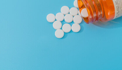 Open pill bottle on blue background