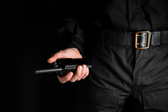 police officer's hand holding a radio station on his belt, close-up. Details about the weapons and special equipment of a police officer or security guard