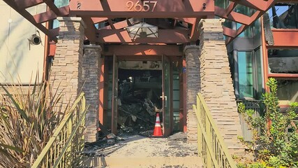 Smooth dolly into remains of care home with handicap sign after fire damage in LA fires, charred walls and debris