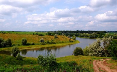 Fototapeta premium Landscapes of wild nature. Unforgettable summer impressions of the beauty of meadows, plantations, water - a slight coolness from the water. A look to the horizon along the sky, where interesting, var