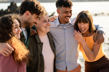 Diverse friends laughing together by the sea on a sunny day