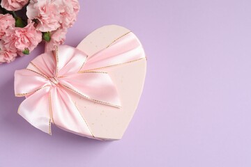 Beautiful bouquet of pink carnations with gift box on a colored background