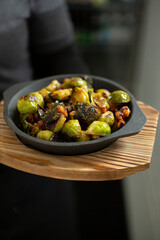 A view of a waitress holding an order of Brussels sprouts.