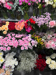 Many different flowers on the shelves of the florist's store