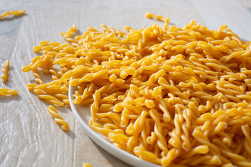 A view of a pile of gluten-free gemelli pasta spilling over a plate.