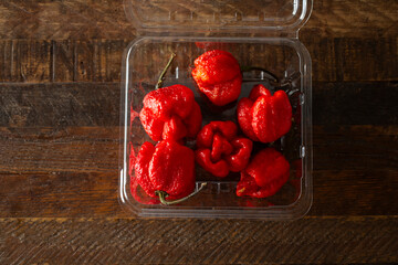 A top down view of a pile of Carolina reaper chili peppers in a plastic container.