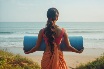 Beautiful Indian woman in her 30s standing with yoga mat near the ocean sea