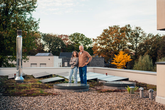 Grandfather and granddaughter on a rooftop with solar panels and greenery